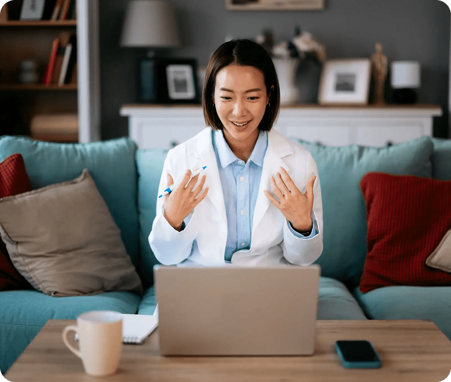A woman video chatting on a laptop, smiling and gesturing.