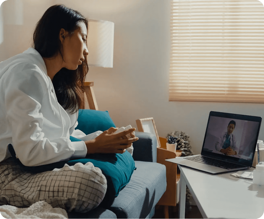 A woman video calling on her laptop from her cozy bed.