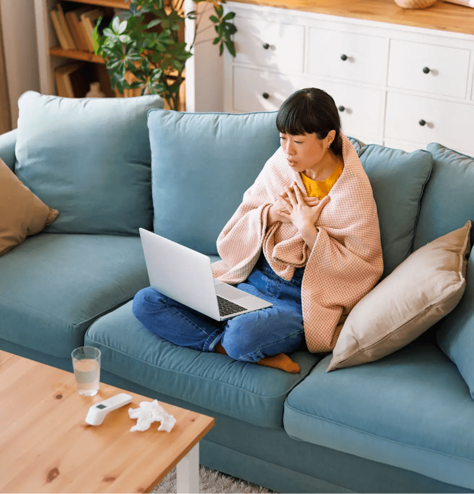 Woman working on laptop while managing a baby at home.